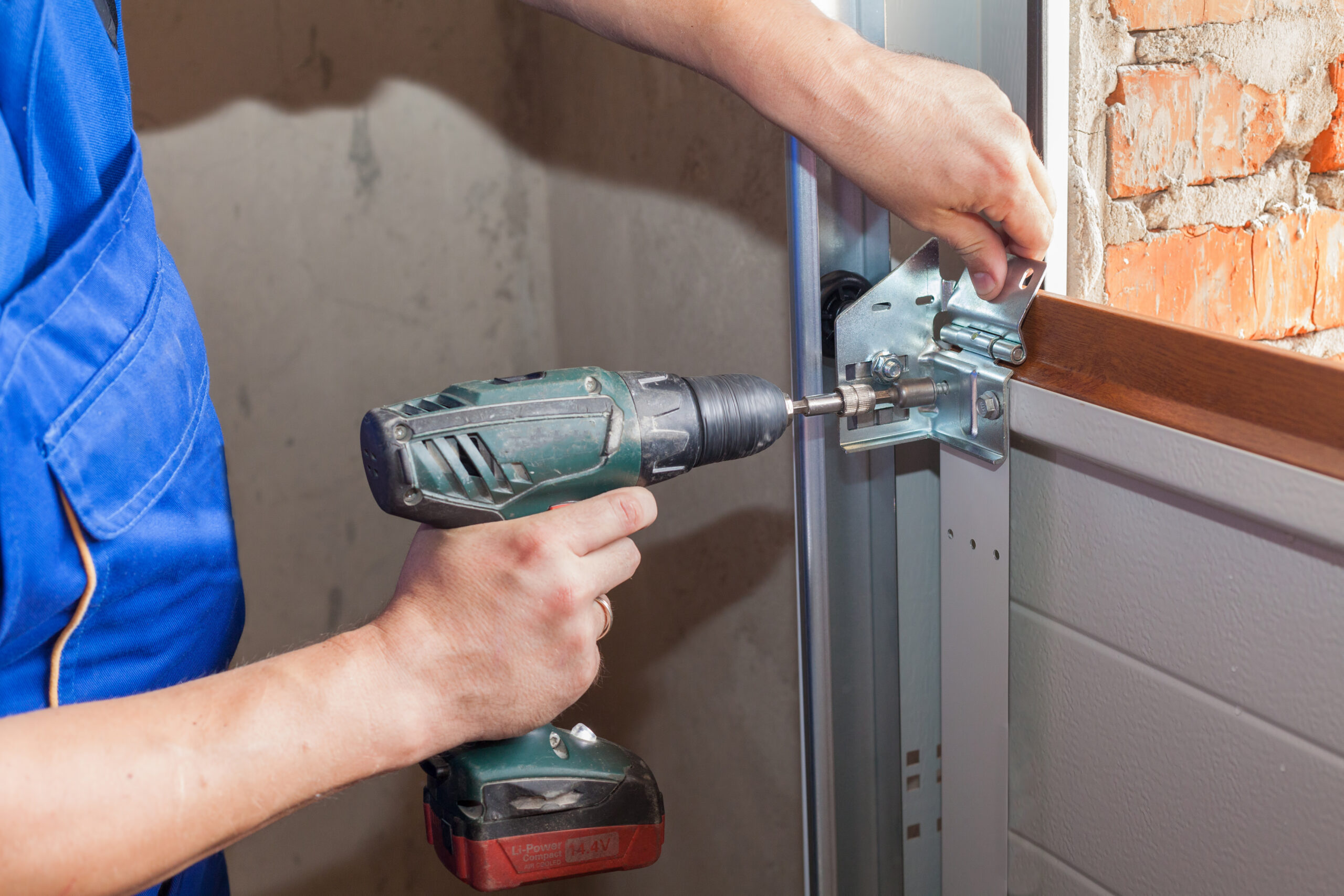 A garage door repair technician installs a garage door