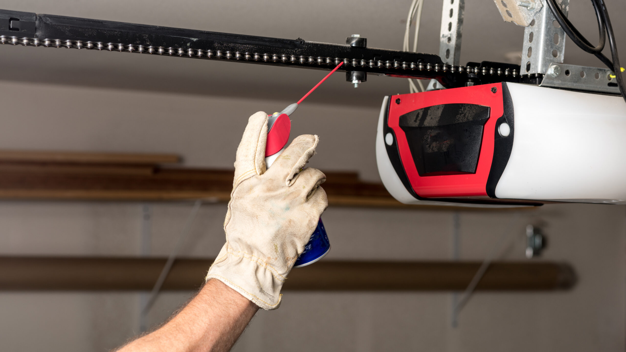 Gloved hand applies oil to a noisy garage door